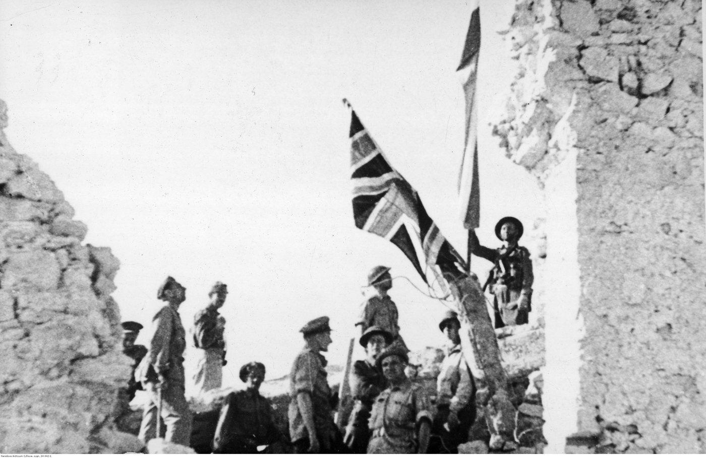 Soldiers gathered among shattered walls of the abbey with a British flag raised above them